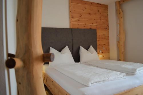 Un dormitorio con una cama con sábanas y almohadas blancas. en Hintnerhof, en Chiusa