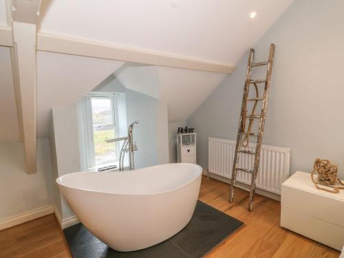 a bathroom with a large white bath tub and a ladder at Fishermans Cottage in Bodorgan
