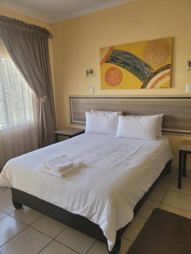 ein Schlafzimmer mit einem großen weißen Bett mit Handtüchern darauf in der Unterkunft Mogale Royal Gardens in Polokwane