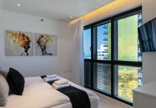 1 dormitorio con cama y ventana grande en YalaRent sea-breeze penthouse with jacuzzi, en Bat Yam