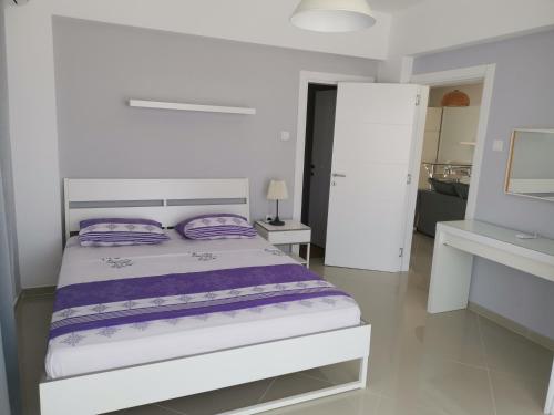 BoghazにあるТрехкомнатные апартаменты в жилом комплексе Caesar Beach D4 Flat13の白いベッドルーム(紫色の枕が付いたベッド付)