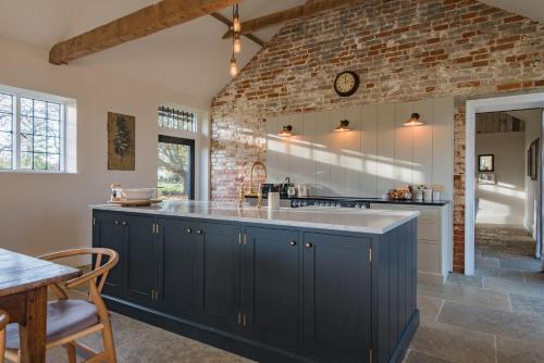 a kitchen with blue cabinets and a brick wall at The Stables in Canterbury