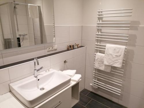ein weißes Badezimmer mit einem Waschbecken und einem Spiegel in der Unterkunft Gasthof Zumdohme in Lastrup