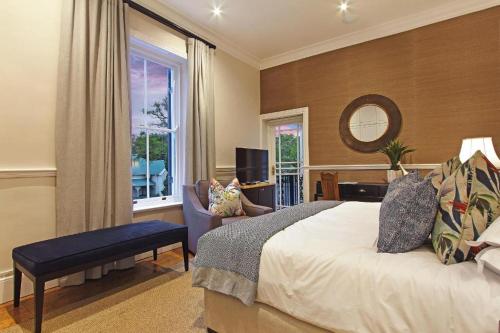 a bedroom with a bed and a chair and a window at Stellenbosch Manor in Stellenbosch