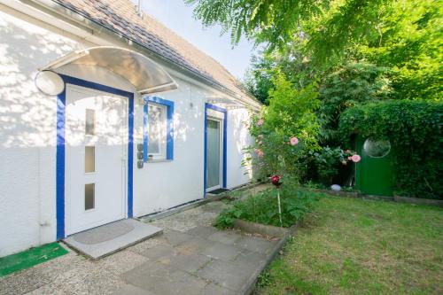 a white house with a blue door and a yard at Tolstov Apartments - 3 Room Apartments with Garden - 20 Min Messe DUS & Airport DUS in Meerbusch