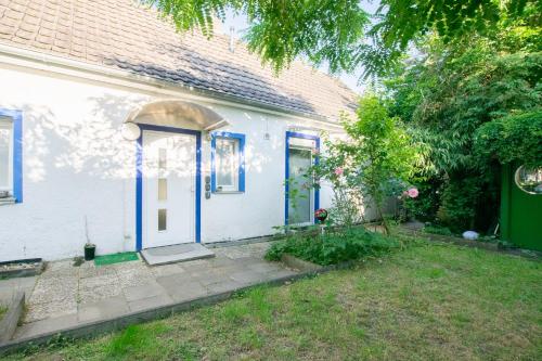a white house with a blue door and a yard at Tolstov Apartments - 3 Room Apartments with Garden - 20 Min Messe DUS & Airport DUS in Meerbusch