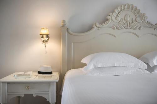 a bedroom with a white bed and a table with a hat on it at Thalassa Boutique Hotel - Adults Only in Lassi