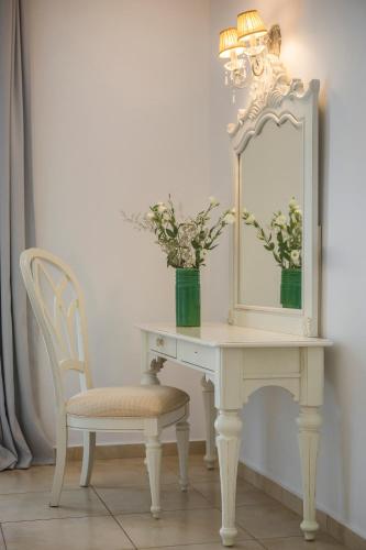 a dressing table with a mirror and a chair with a vase of flowers at Thalassa Boutique Hotel - Adults Only in Lassi