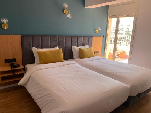 Royal Hotel Rabat في الرباط: سرير كبير بملاءات بيضاء ومخدات صفراء