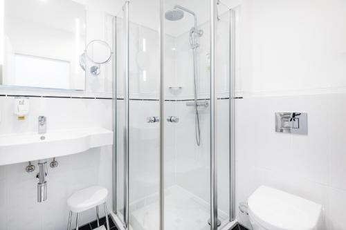 a white bathroom with a shower and a sink at Hotel Kronprinz Berlin in Berlin