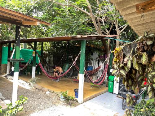 a man sitting in hammocks under a house at Palomino Hostel in Palomino