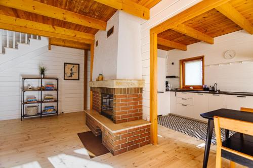 a kitchen with a brick fireplace and wooden ceilings at Dom pod Klonem in Jantar