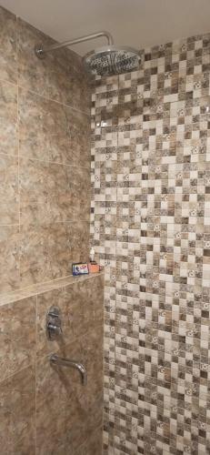 a bathroom with a shower with a tile wall at Ruby Apartment #9 in Yogyakarta