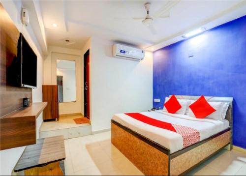 Hotel Sangam في أحمد آباد: غرفة نوم بسرير ومخدات حمراء وتلفزيون