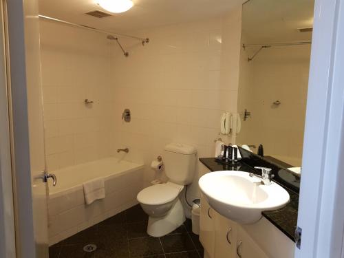 a bathroom with a toilet and a sink and a tub at Parramatta Hotel Apartment in Sydney