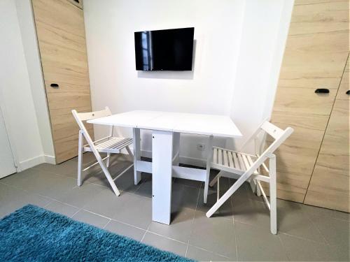 a white table and chairs with a tv on a wall at Les Halles Appartements in Paris