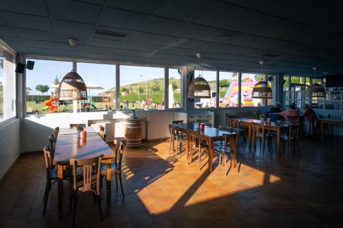 un restaurante con mesas y sillas y muchas ventanas en Kampaoh Castrillón, en Naveces