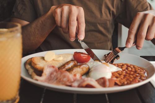 Eine Person isst einen Teller mit Frühstücksprodukten in der Unterkunft Sketchley Grange Hotel in Hinckley