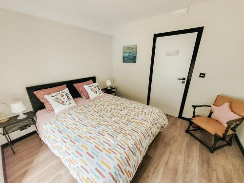 a bedroom with a bed and a chair and a door at Au bout de mes rêves in Walcourt