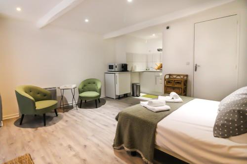 Cet appartement comprend une chambre avec un lit et deux chaises ainsi qu'une cuisine. dans l'établissement Le Coin Tranquille de Sarlat, à Sarlat-la-Canéda