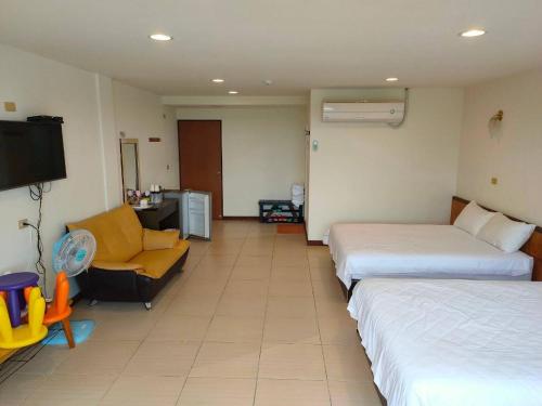 a hotel room with two beds and a chair and a tv at Julie's Garden in Hengchun