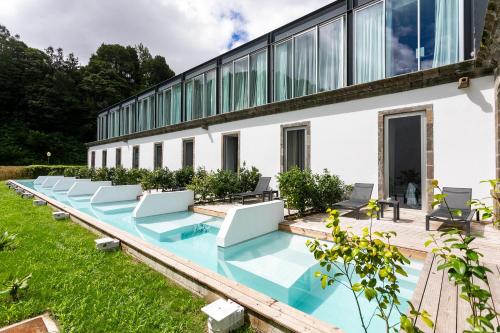 a swimming pool with chairs and a building at Octant Furnas in Furnas