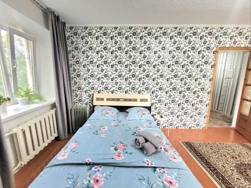 1 dormitorio con cama azul y papel pintado con motivos florales en 1 комн. Апартаменты на Назарбаева 72, en Kokshetau