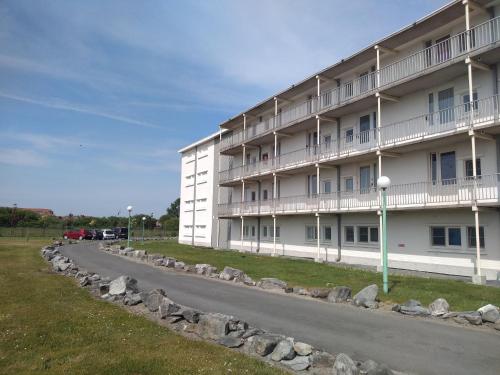 a large white building with a road in front of it at Joy Lotus 105 in De Haan