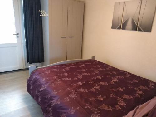 a bedroom with a bed with a purple blanket at Joy Lotus 105 in De Haan