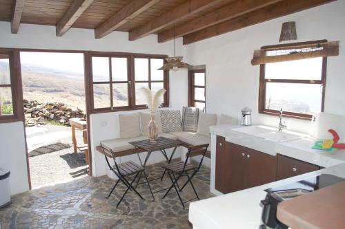 a kitchen with a table and chairs and windows at Casa Los Llanos in Playa de Santiago