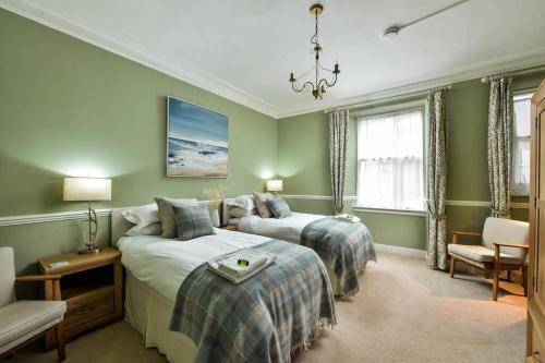 een groene slaapkamer met 2 bedden en een kroonluchter bij 8b Howard Place in St Andrews