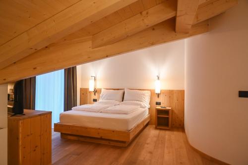 sypialnia z łóżkiem i drewnianą podłogą w obiekcie B&B Fontanella w mieście San Lorenzo in Banale
