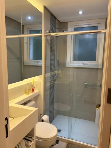 uma casa de banho com uma cabina de duche em vidro e um WC. em Apartamento novinho na Borges de medeiros- CENTRO em Gramado