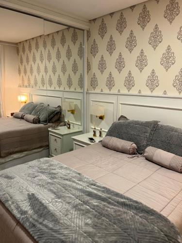 um quarto com 2 camas e um espelho em Apartamento novinho na Borges de medeiros- CENTRO em Gramado
