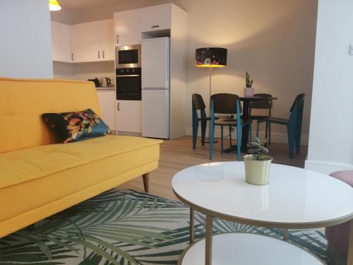 a living room with a yellow couch and a table at 360 Town Stay Apartments & Studios in Dungarvan