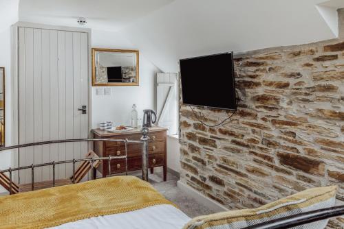 a bedroom with a stone wall with a tv on it at The Olde Malthouse Inn in Tintagel