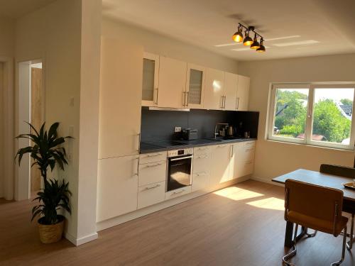 a kitchen with white cabinets and a table with a plant at bike & chill in Kleve
