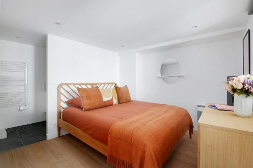 a bedroom with a bed with an orange blanket at CMG - Passy - La Muette in Paris