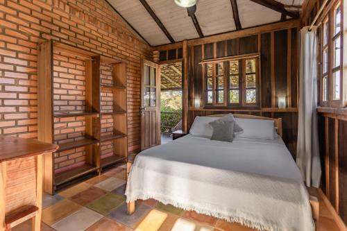 a bedroom with a bed and a brick wall at Pousada Meia Lua in Praia do Rosa