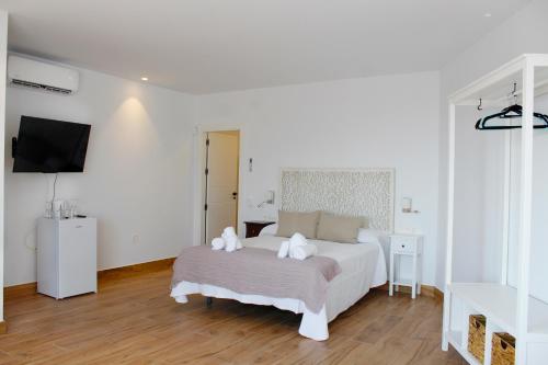 ein weißes Schlafzimmer mit einem Bett und einem TV in der Unterkunft Suite Émber-Fuego in Soportújar
