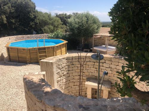 a pool in a yard with a stone wall at La casa Bianca in Bonifacio