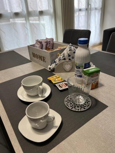 a table with plates and cups and a bottle of water at Bicocca Flat B in Milan