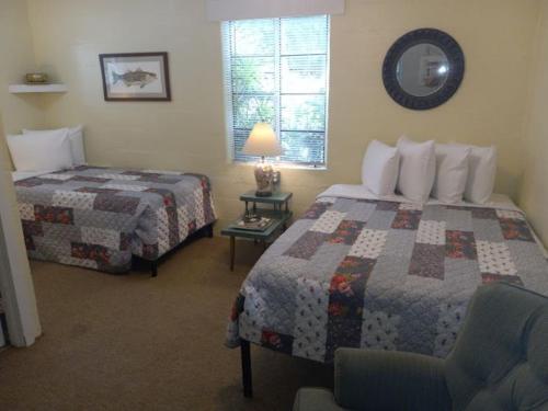 a bedroom with two beds and a lamp and a chair at Stegbone's Fish Camp and Resort in Satsuma