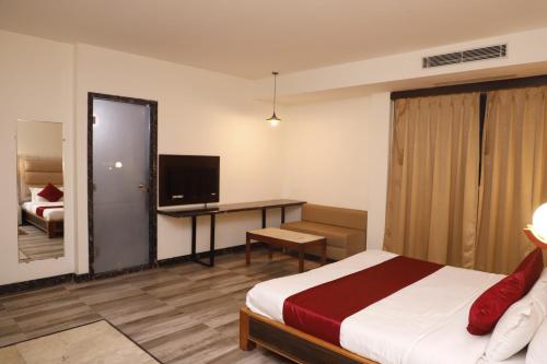 a hotel room with a bed and a desk and a television at The Jamun Tree in Muzaffarpur