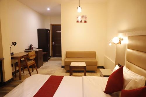 a hotel room with a bed and a chair and a table at The Jamun Tree in Muzaffarpur