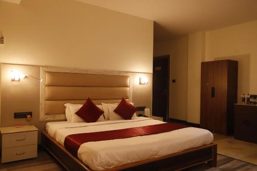 a bedroom with a large bed with red pillows at The Jamun Tree in Muzaffarpur