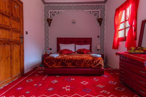 a bedroom with a bed with a red bedspread at Amazigh Family Riad in Imlil