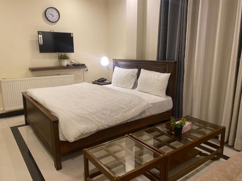 a bedroom with a bed and a table and a clock at AK Hotel & Suites in Murree