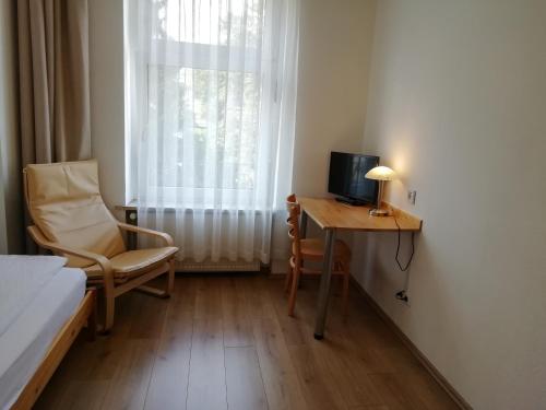 a bedroom with a desk and a bed and a window at Hotel Hanseatic-garni in Wuppertal