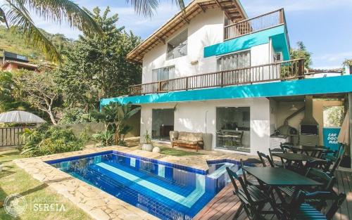 a villa with a swimming pool in front of a house at Casa completa com vista na praia do Curral in Ilhabela